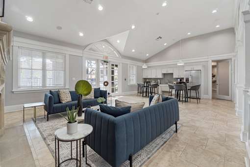 A living room with a grey sofa and a round table with a plant on it.