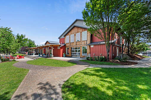 A building with a red and brown exterior is surrounded by a grassy area and a paved walkway.