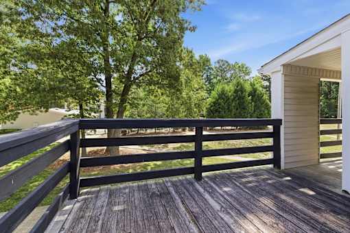 A wooden deck with a railing and a house in the background.