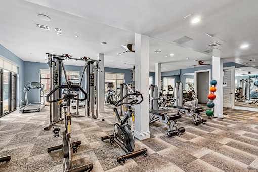 A spacious gym with a variety of equipment including treadmills, elliptical machines, and weight machines.