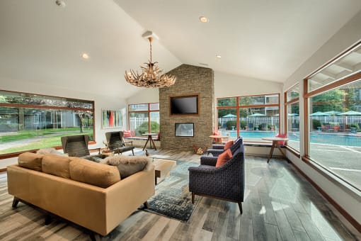 Clubhouse seating area with stone fireplace and pool views at Canyon Creek Apartments, Wilsonville, OR 97070