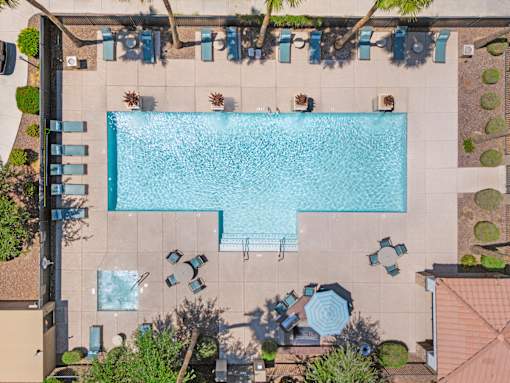 A large rectangular pool surrounded by chairs and plants.