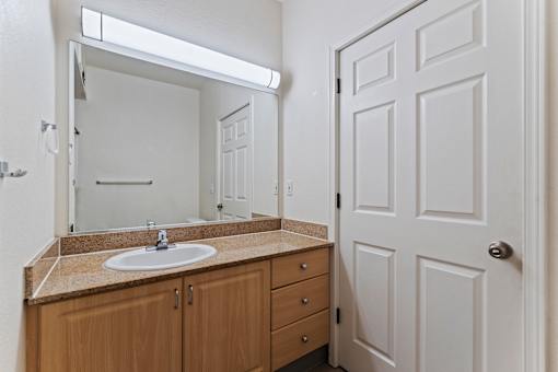 A bathroom with a sink, mirror, and wooden cabinets.