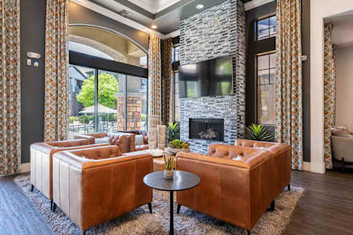 A living room with a stone fireplace and a brown leather couch.