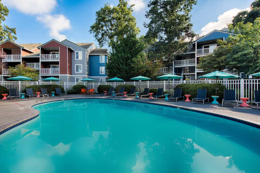 Large outdoor pool with lounge chairs and colorful tables at Canyon Creek Apartments, Wilsonville, 97070