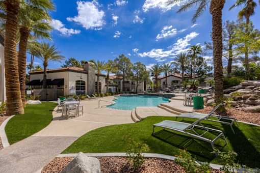 A pool surrounded by palm trees and a sun lounger.