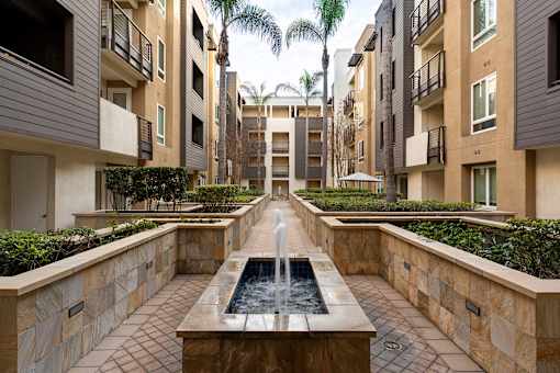 A long rectangular fountain in the middle of a courtyard surrounded by buildings.