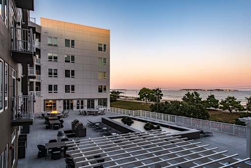 a view of the courtyard of a building overlooking the ocean at sunset