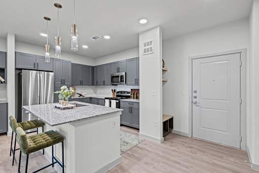 A kitchen with a white island and green chairs.