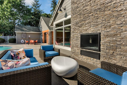 Outdoor lounge area with fireplace and wicker seating at Canyon Creek Apartments, Oregon