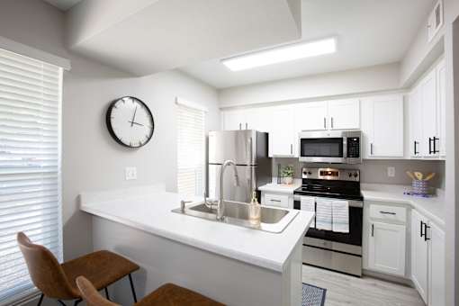 A modern kitchen with a stove, sink, and cabinets.