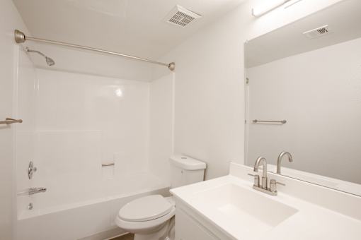 A white bathroom with a toilet, sink, and shower.