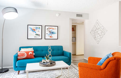 A living room with a blue couch, a white coffee table, and a lamp.