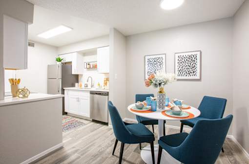 A dining room with a table set for two and a kitchen area in the background.