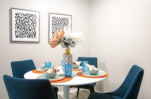 A dining table with blue chairs and a vase of flowers.