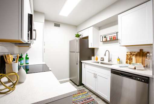 A modern kitchen with white cabinets and a stainless steel refrigerator.