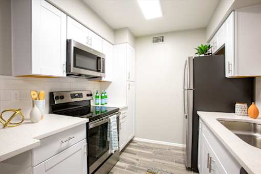 A kitchen with white cabinets and a black refrigerator.
