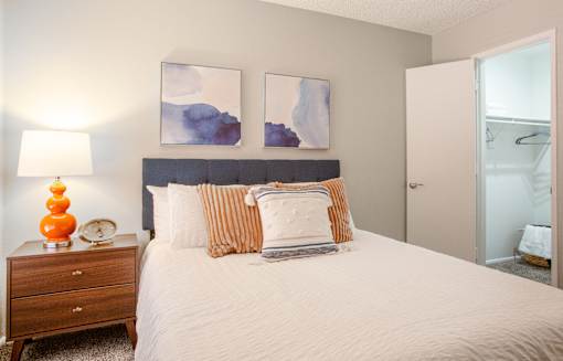 A bedroom with a bed, nightstand, and two paintings on the wall.