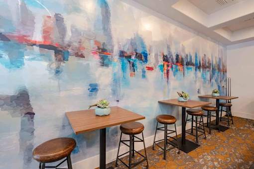 A room with a wall mural and a table with four stools.