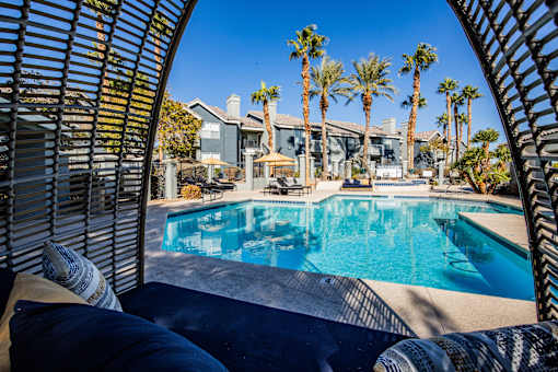 A pool surrounded by palm trees and a patio area.