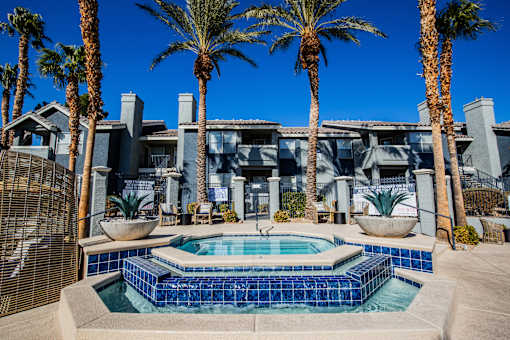A pool surrounded by palm trees and a building in the background.