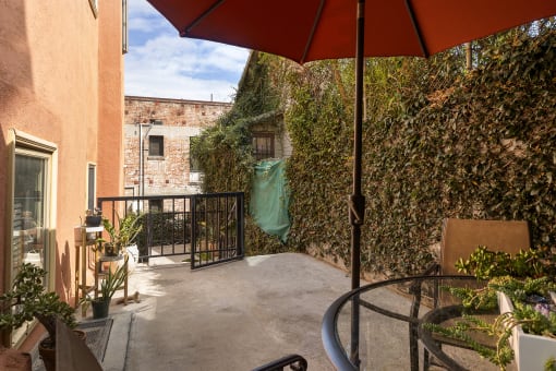 a patio with a red umbrella and a black table and chairs at Delta, Los Angeles