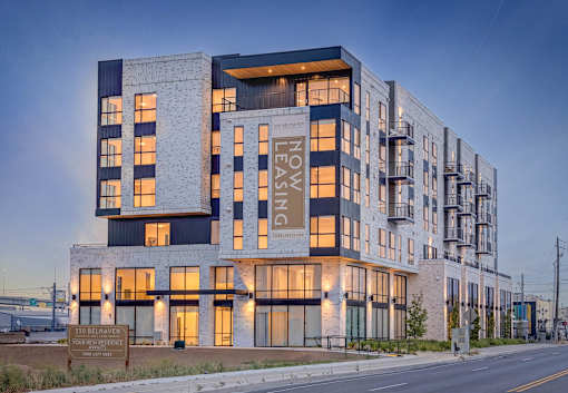 A modern building with the words "LEASING" and "NOW" on its facade.