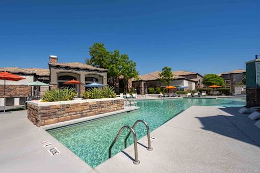 A pool surrounded by a stone wall with a building in the background.