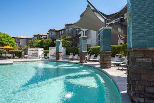 A swimming pool surrounded by stone pillars and lounge chairs.