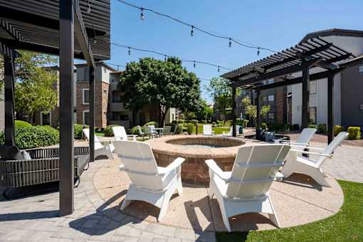 A patio with white chairs and a fire pit.
