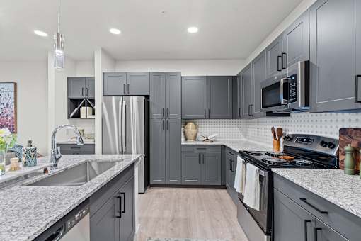 A modern kitchen with grey cabinets and a white countertop.