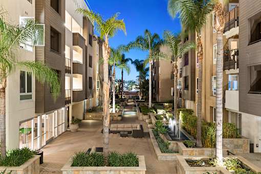 A courtyard with palm trees and a fountain in the middle.