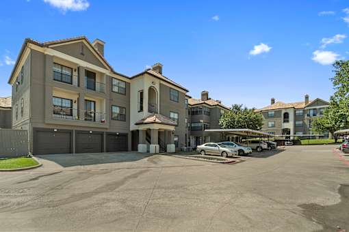 A large apartment complex with a parking lot in front.