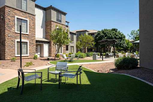 A sunny day at a residential complex with a green lawn and a bench.
