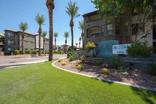 A grassy area in front of apartment buildings with a sign that says Zone 4455.