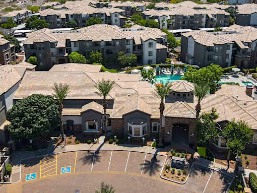 A view of apartment buildings with a pool and palm trees.