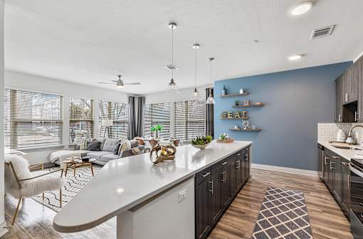 A modern kitchen with a white island and a dining area with a white chair.