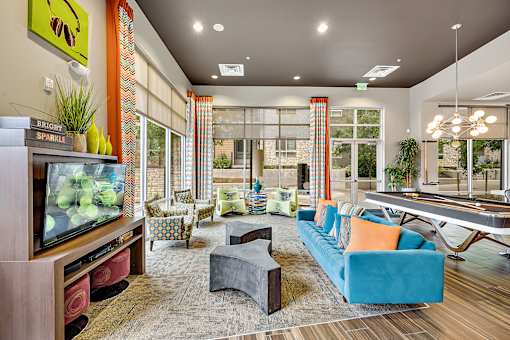 A living room with a television, couch, and pool table.