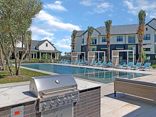 A BBQ grill is on a patio next to a pool.