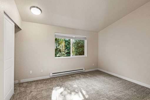 Empty bedroom with carpet and window view at Hubbard's Crossing Apartments, Kirkland, WA