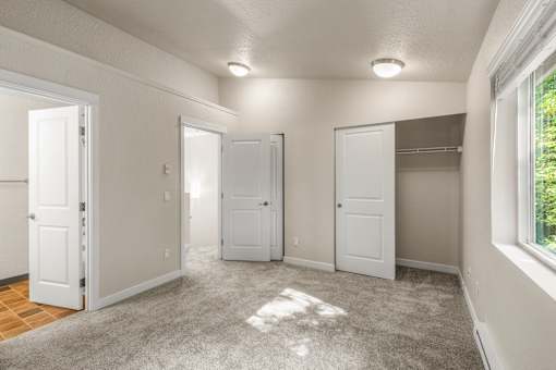 Empty bedroom with walk-in closet and carpet at Hubbard's Crossing Apartments, Kirkland, 98034