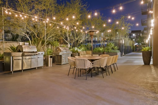 a patio with a table and chairs and strings of lights
