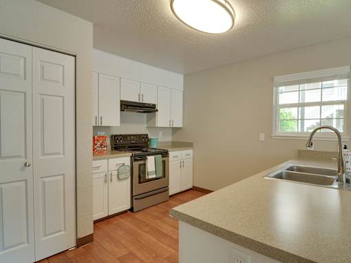 A kitchen with white cabinets and a wooden floor.