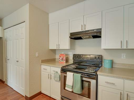 A kitchen with white cabinets and a stove top oven.