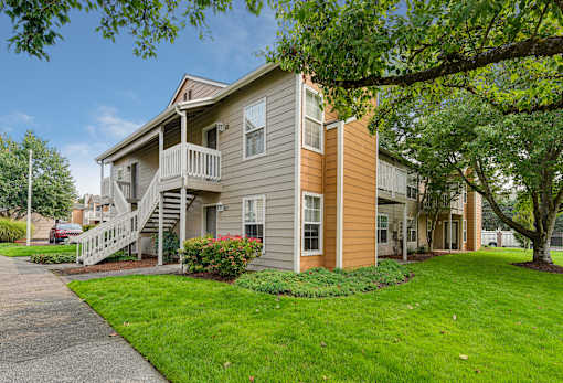 A two-story house with a balcony and a tree in front.