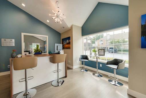 A reception area with a white counter and brown chairs.