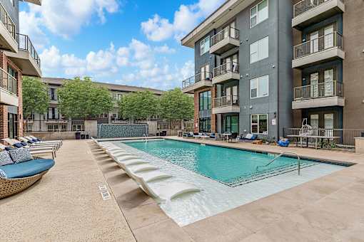 A large swimming pool is surrounded by apartment buildings.
