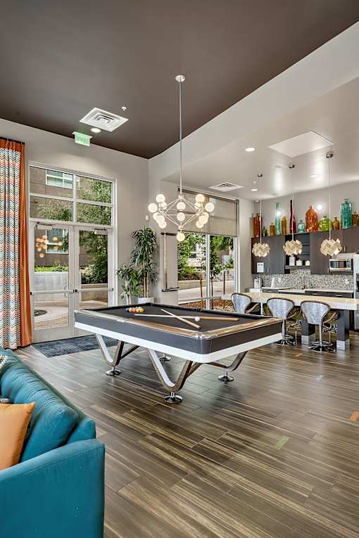 A pool table is in the middle of a room with a blue couch.
