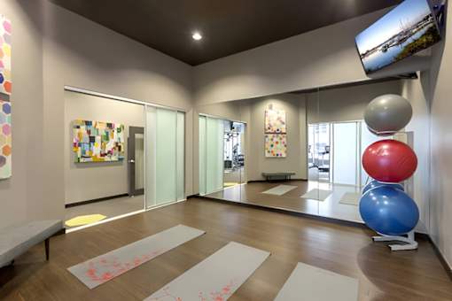 A yoga studio with a large mirror, exercise balls, and yoga mats.