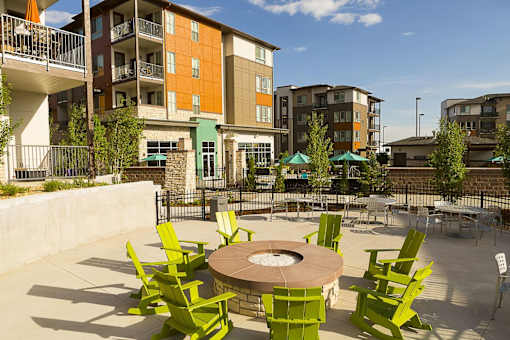 Green chairs are arranged around a circular table in the middle of a patio.